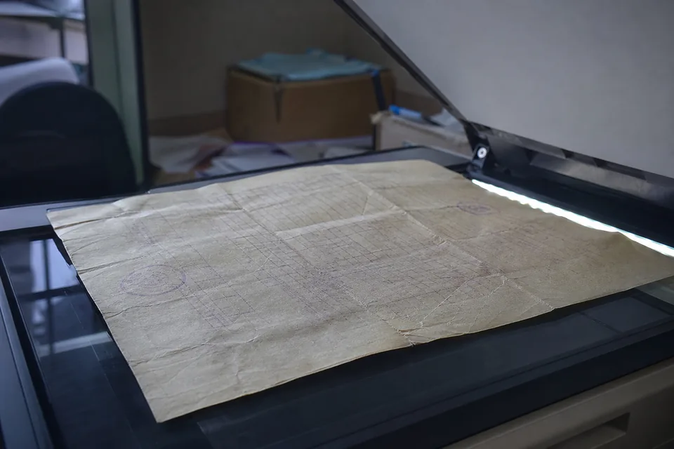 A creased, stamped paper form under the open lid of a flatbed scanner